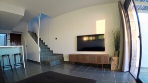 A modern living room with a flat-screen TV, a staircase, and a seating area. - ALTOS DE ARGUINEGUÍN (Mogán Arguineguín)