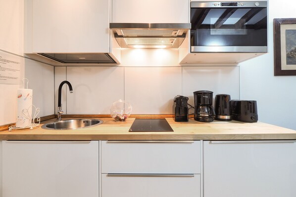 A modern kitchen with a stainless steel sink, a built-in range hood, and a microwave above the stove.