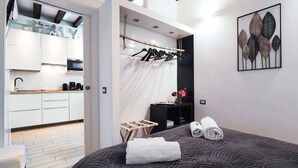 A modern bedroom with a large bed, a wardrobe, and a bathroom visible through an open door.