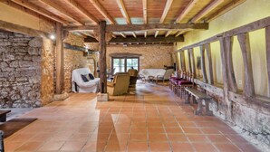 Un interior rústico con paredes de piedra, vigas de madera y suelo de baldosas.