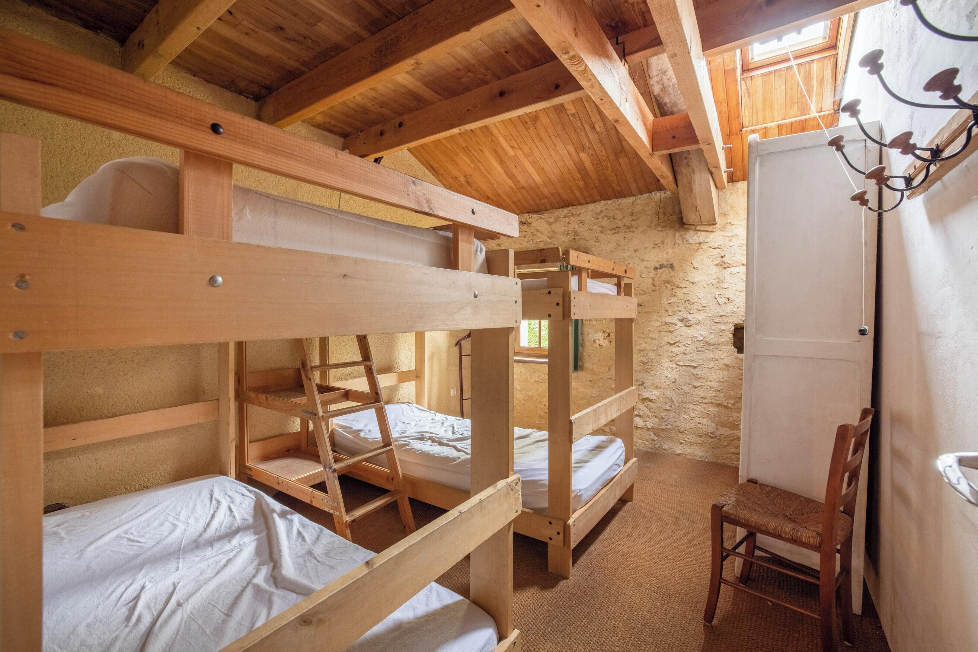 A rustic wooden room with bunk beds, a chair, and a white door.