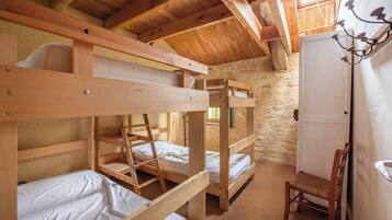 A rustic wooden room with bunk beds, a chair, and a white door.