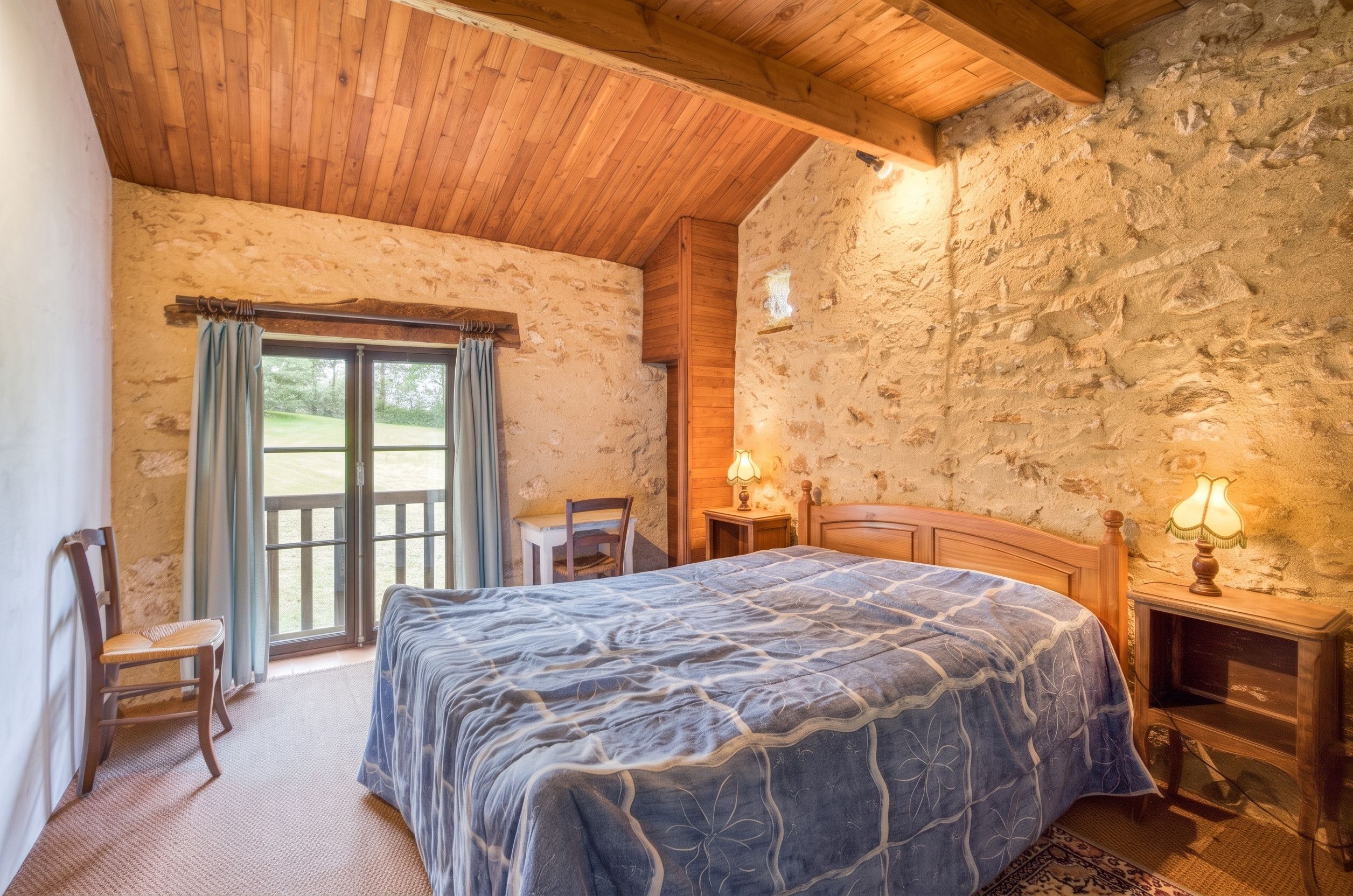 Ein Schlafzimmer mit einem Bett, einem Sessel, einem Tisch mit Lampe und einer Steinsäule.