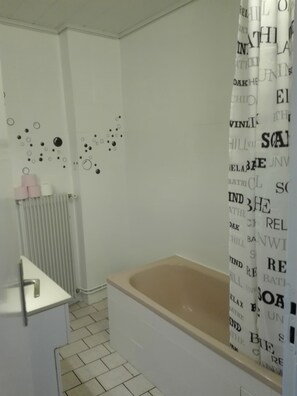A bathroom with a bathtub, a toilet, and a sink. There are decorative wall stickers and a shower curtain with text.