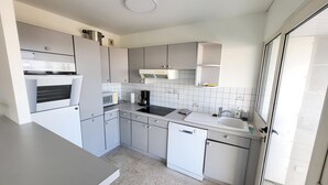 A modern kitchen with a built-in oven, microwave, and dishwasher, featuring grey cabinets and a tiled backsplash.