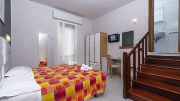 A hotel room with a bed, a desk, a chair, a television, and a staircase.