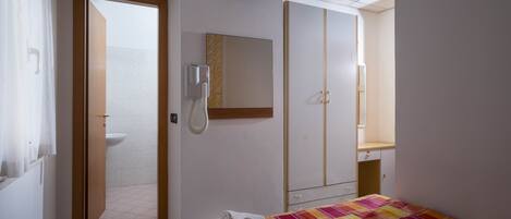 Ein Hotelzimmer mit Bett, Fernseher, Kleiderschrank und einem durchgegangenen Tür sichtbaren Badezimmer.