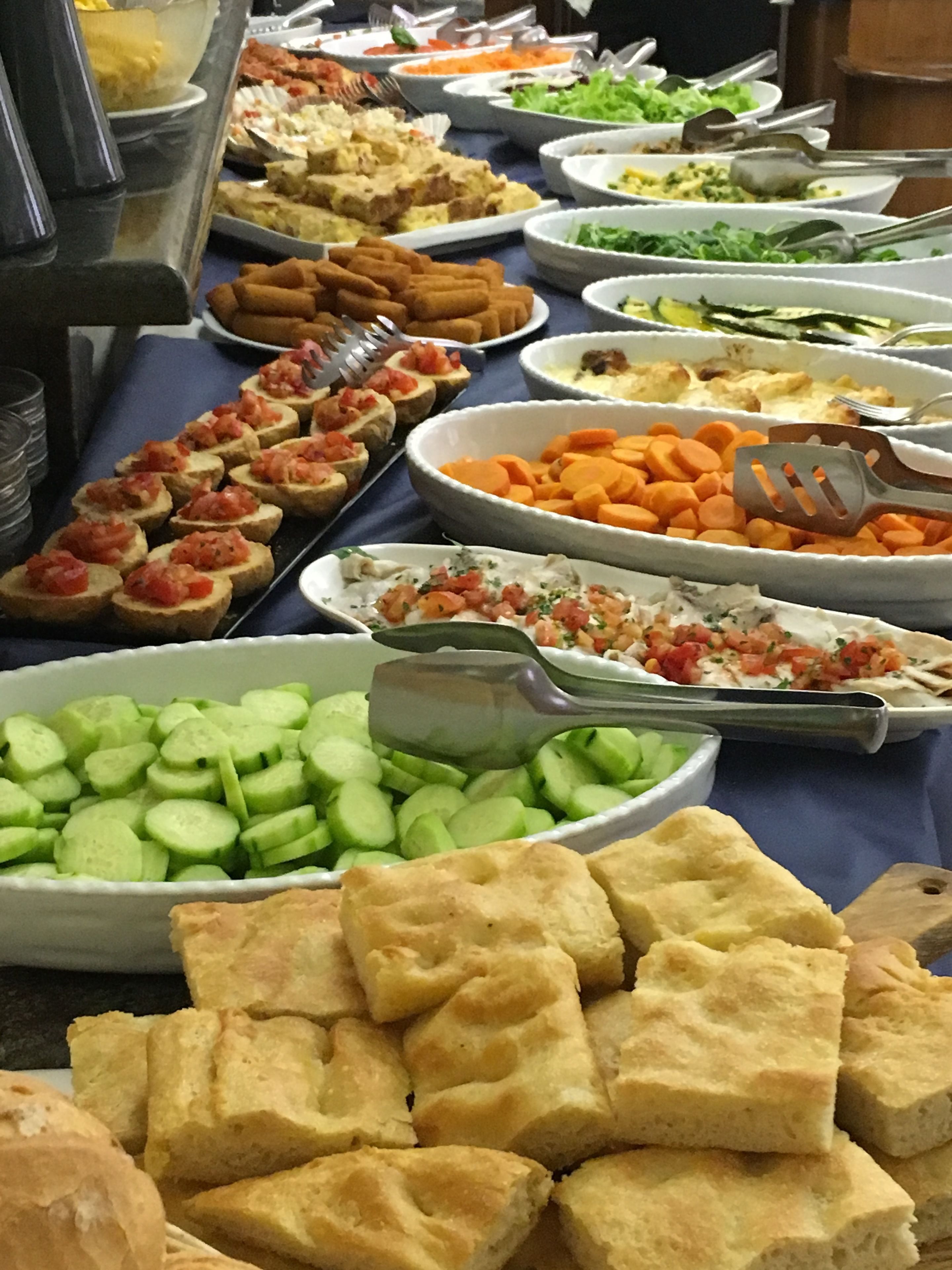A buffet table with various food items including bread, vegetables, and dips.