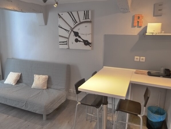 A modern living space with a grey sofa, a white desk, and a large wall clock.