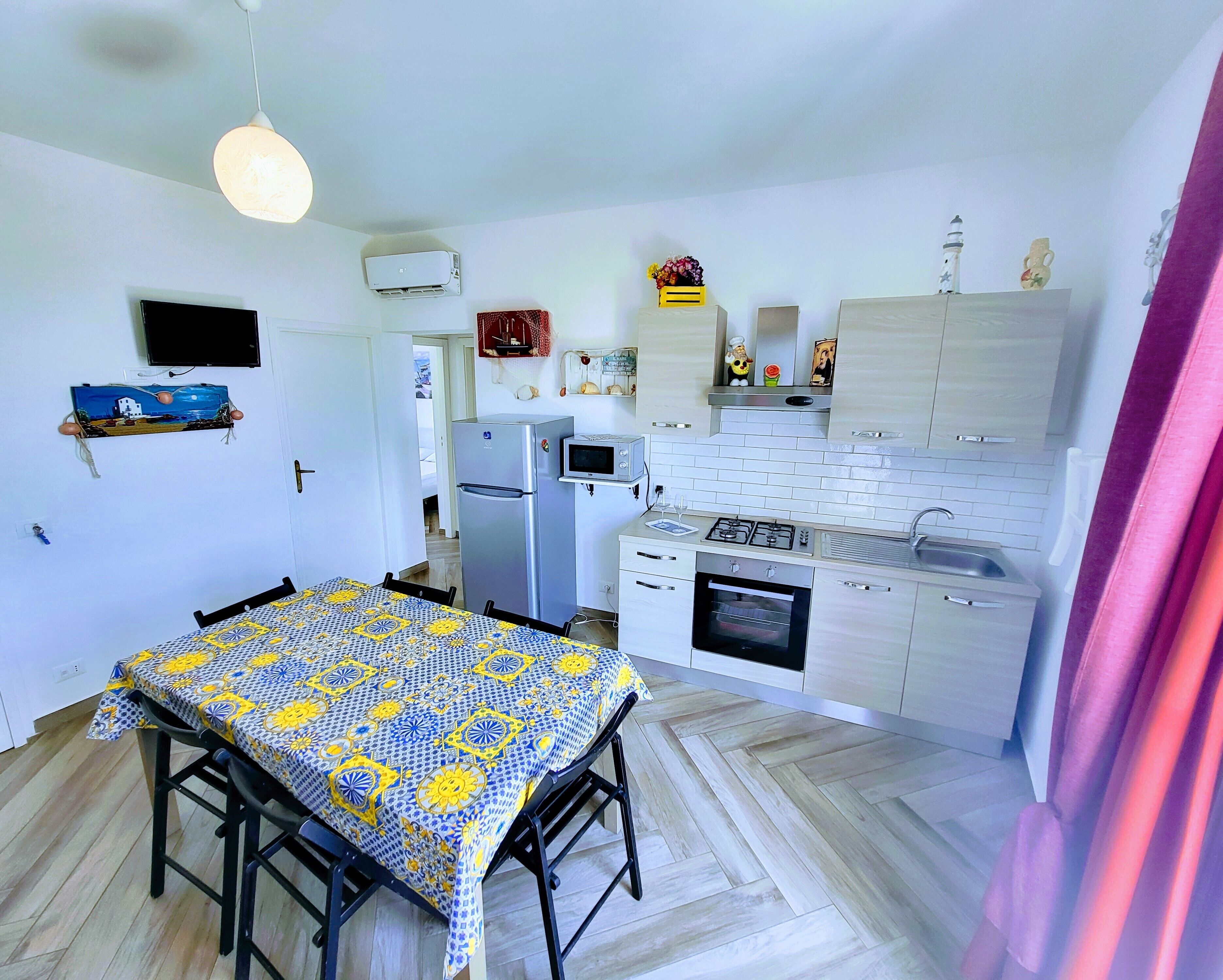 Una cucina compatta con zona pranzo, frigorifero, forno a microonde e piano cottura.