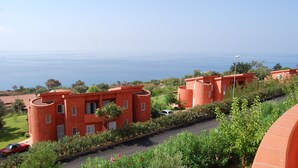 A coastal residential area with red buildings, a road, and a view of the sea.