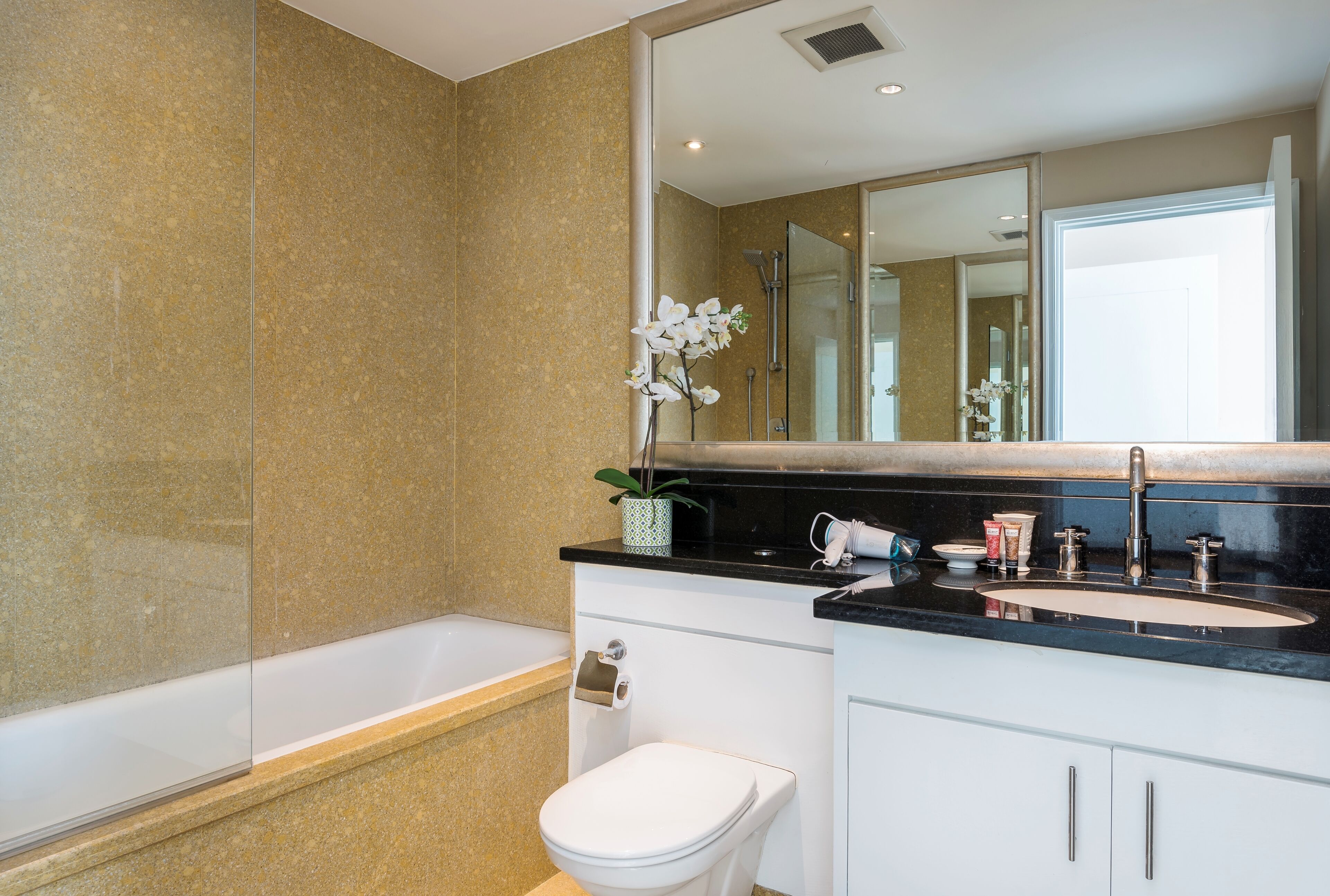 A modern bathroom with a bathtub, toilet, sink, and a large mirror.