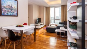 Habitació d'hotel moderna amb zona de menjador, espai de descans i una finestra gran que ofereix vista a la ciutat.