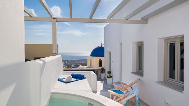 Un espace piscine aménagé sur le toit, offrant une vue sur un bâtiment à coupole bleue, des murs blancs et un ciel dégagé.