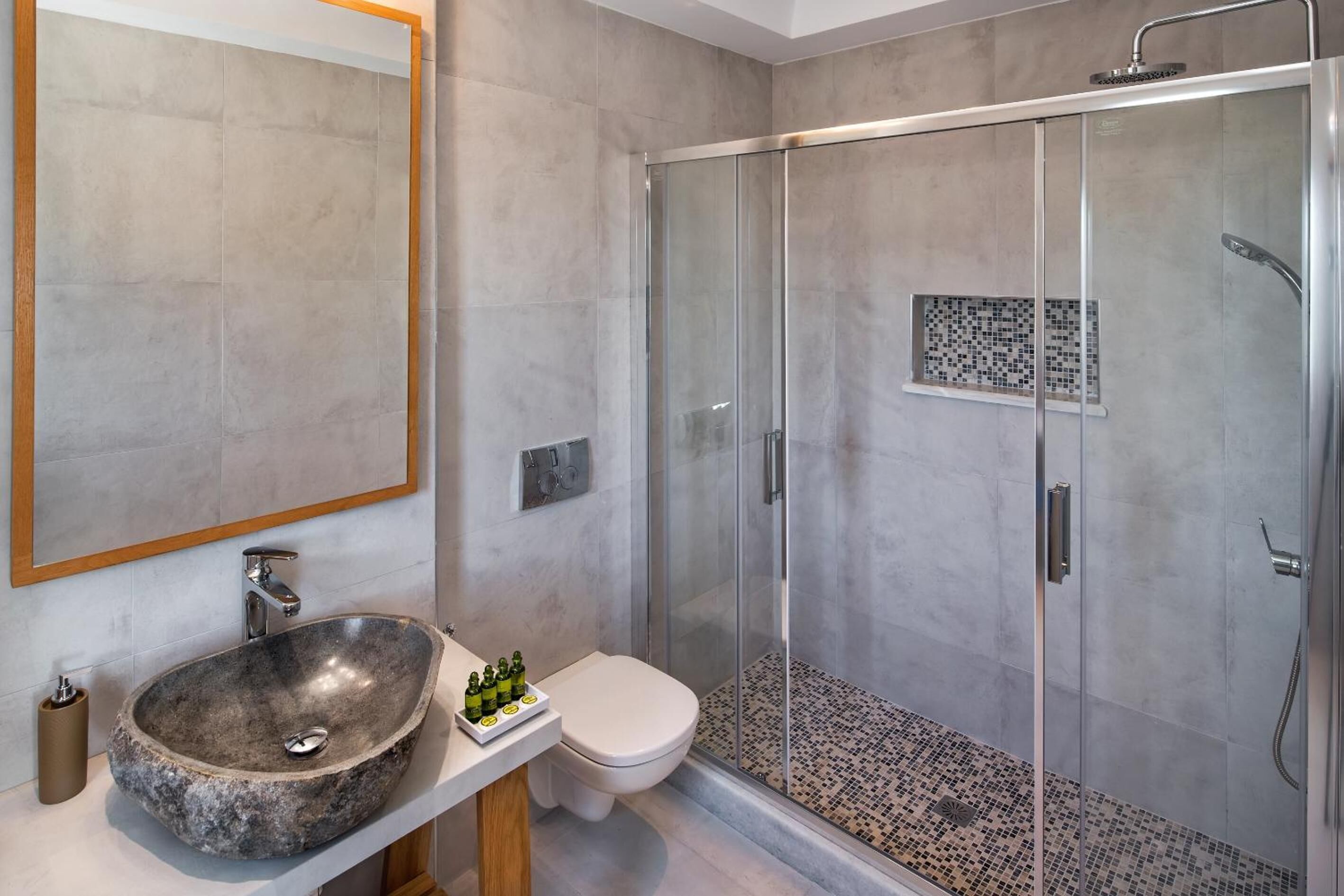 Une salle de bain moderne avec un lavabo en pierre, des toilettes et une douche séparée par une paroi de verre.