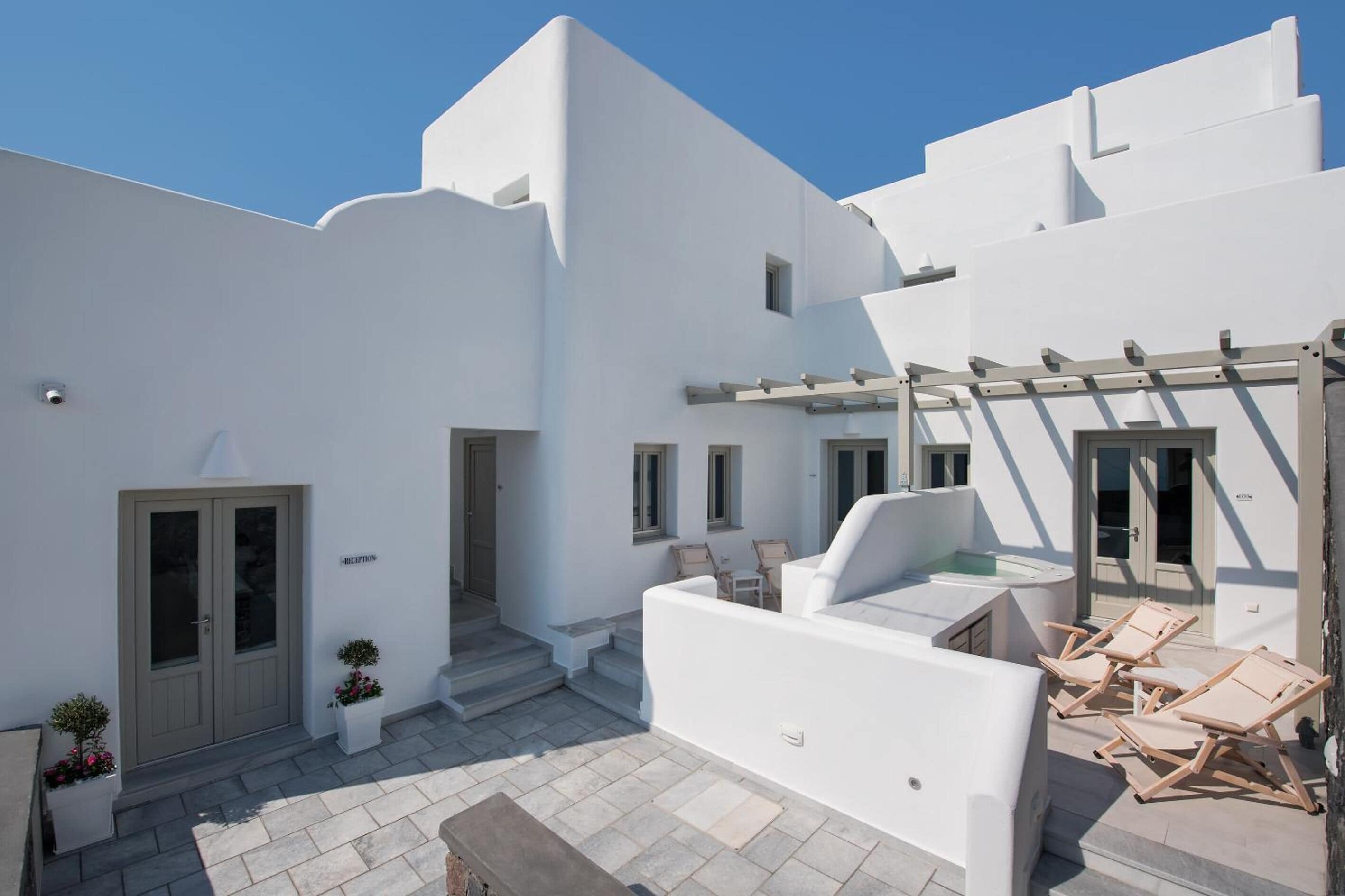 Un edificio blanco con un patio, asientos al aire libre y un jacuzzi.