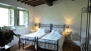 A double bed with white linens, two bedside tables with lamps, a wicker chair, and a wooden floor. - A luxury escape in Chianti, great landscape, stunning views, swimming pool (San Polo in Chianti)