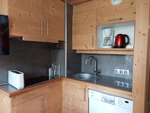 Efficient kitchen with dishwasher, stainless steel sink, and coffee maker.