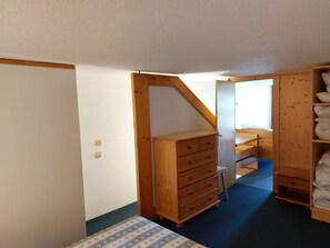 Cozy retreat with a small bed, wooden wardrobe, and shelf unit.