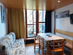 Relax in a simple, functional room with a large window offering a view of the balcony and lush greenery.