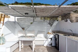 Una cucina esterna compatta con zona pranzo, inclusi tavolo e sedie, e un lavello.