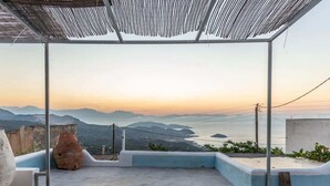 A terrace with a view of mountains and a body of water during sunset.