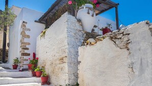 A white-washed building with a stone staircase and red flower pots.