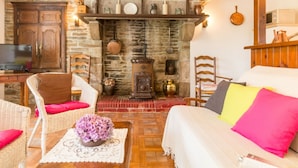 Um quarto aconchegante com lareira de pedra, móveis de vime e uma cama com almofadas coloridas.