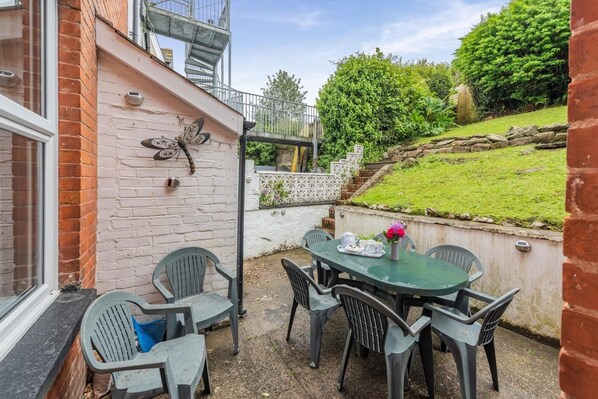 Une terrasse avec une table et des chaises, une décoration en forme de papillon sur le mur et une vue sur le jardin.
