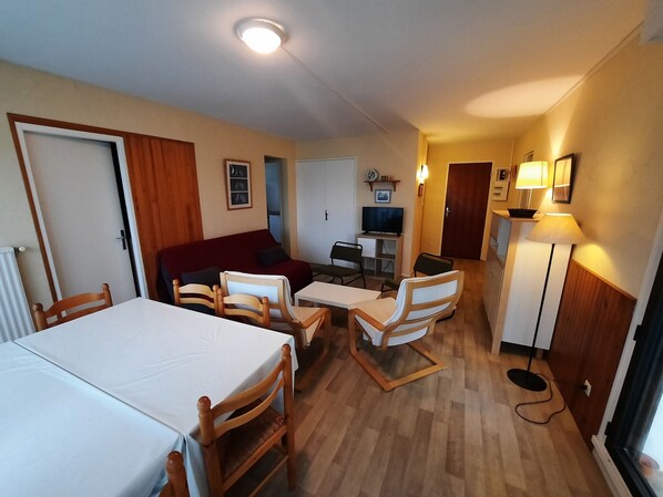 A compact room with a bed, a sofa, a dining table, and a TV. - Spacious Apartment with Terrace in Seignosse - Close to Beach and Amenities (Seignosse)