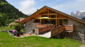 Un chalet en bois doté d’un balcon, de murs en pierre et offrant une vue sur les montagnes.