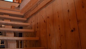 Un escalier en bois, surmonté d’une lucarne, qui mène à un niveau supérieur.