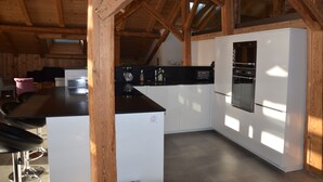 Une cuisine moderne avec des poutres en bois, un îlot central et des appareils électroménagers intégrés.