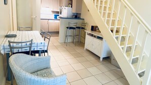 A compact kitchen with a dining area, a staircase, and a small seating area.