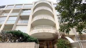 A multi-story residential building with a central entrance, a sign indicating 'Residence L'Amiral', and a staircase leading to the entrance.