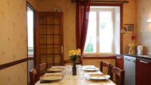 A dining area with a table set for four, a window with curtains, and a kitchen area with a dishwasher.
