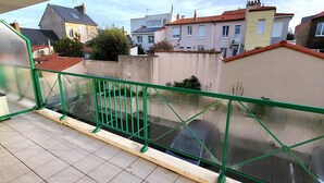 A balcony with a green metal railing, a tiled floor, and a view of neighboring houses. - Charming apt with terrace, parking, near beach and shops (Les Sables-d'Olonne)