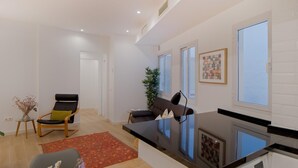 Een moderne woonkamer met een bank, een stoel, een kleine tafel met een vaas en een wasmachine.