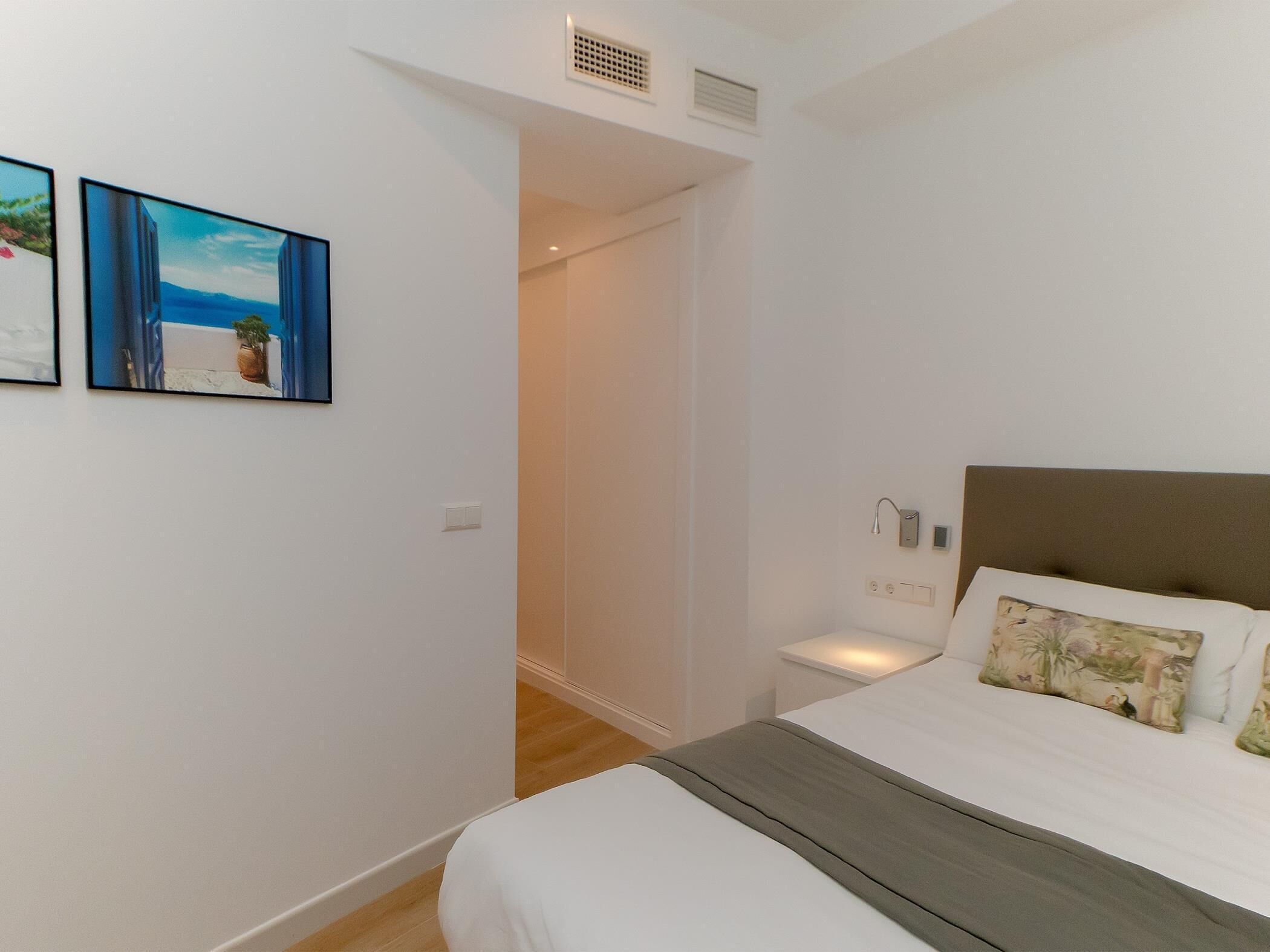 Une chambre à coucher comprenant un lit, des tables de chevet et une porte donnant sur une salle de bain.