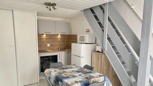 Eine kleine Küche mit Essbereich, einer Mikrowelle, einem Toaster und einer Treppe.