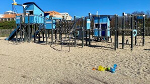 Ein Spielplatz mit Klettergerüsten und Rutschen, umgeben von Sand.