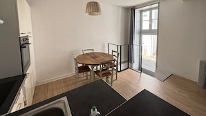 Una cocina moderna con una mesa de comedor de madera, sillas y una lámpara colgante.