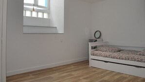 Un dormitorio con una cama individual, una ventana y un espejo en la pared.