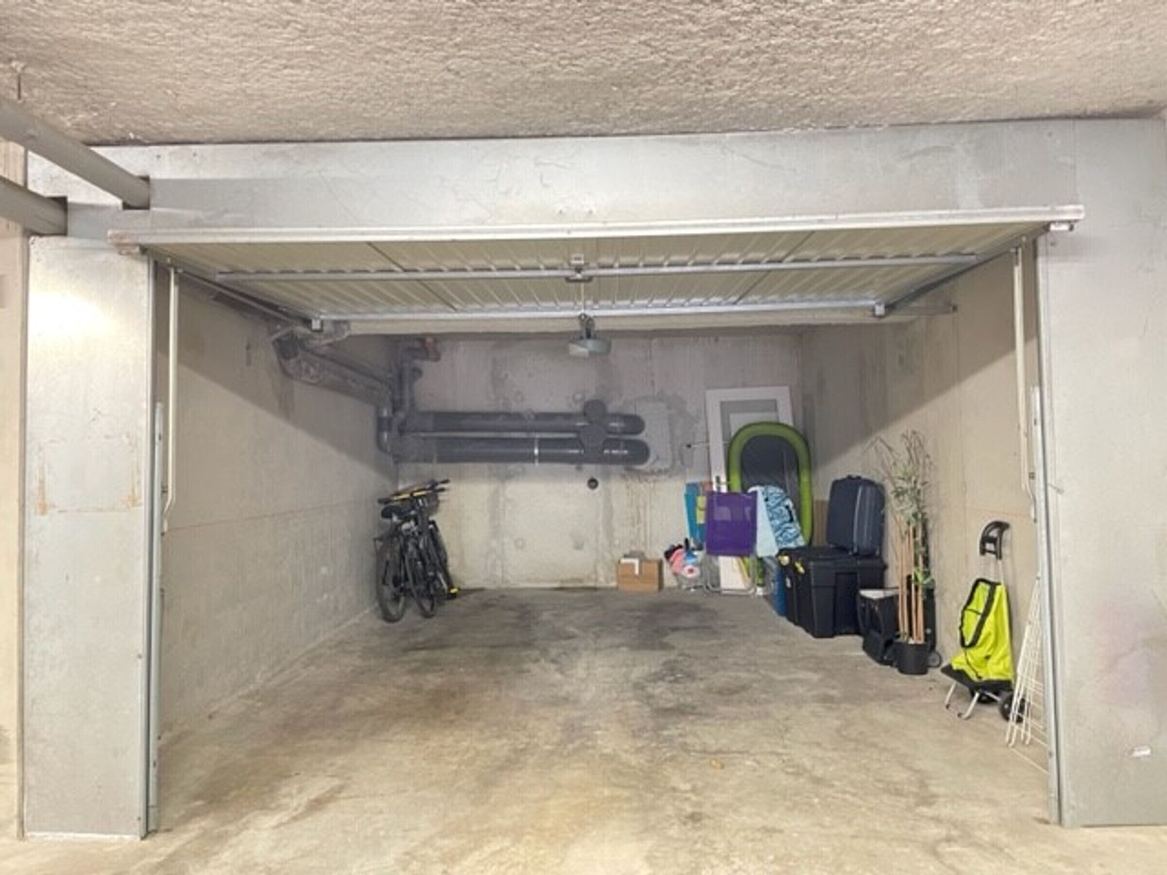 Un garaje con piso de concreto, una bicicleta y varias bolsas y cajas.