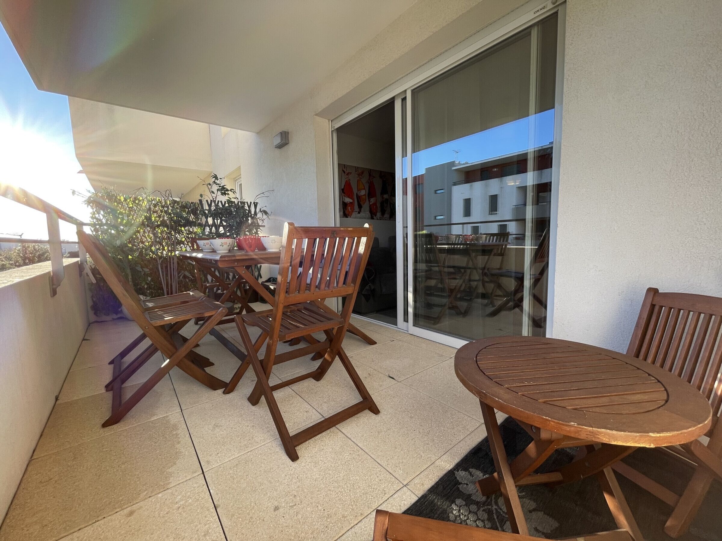 A balcony with wooden furniture, including a table and chairs, and a potted plant.