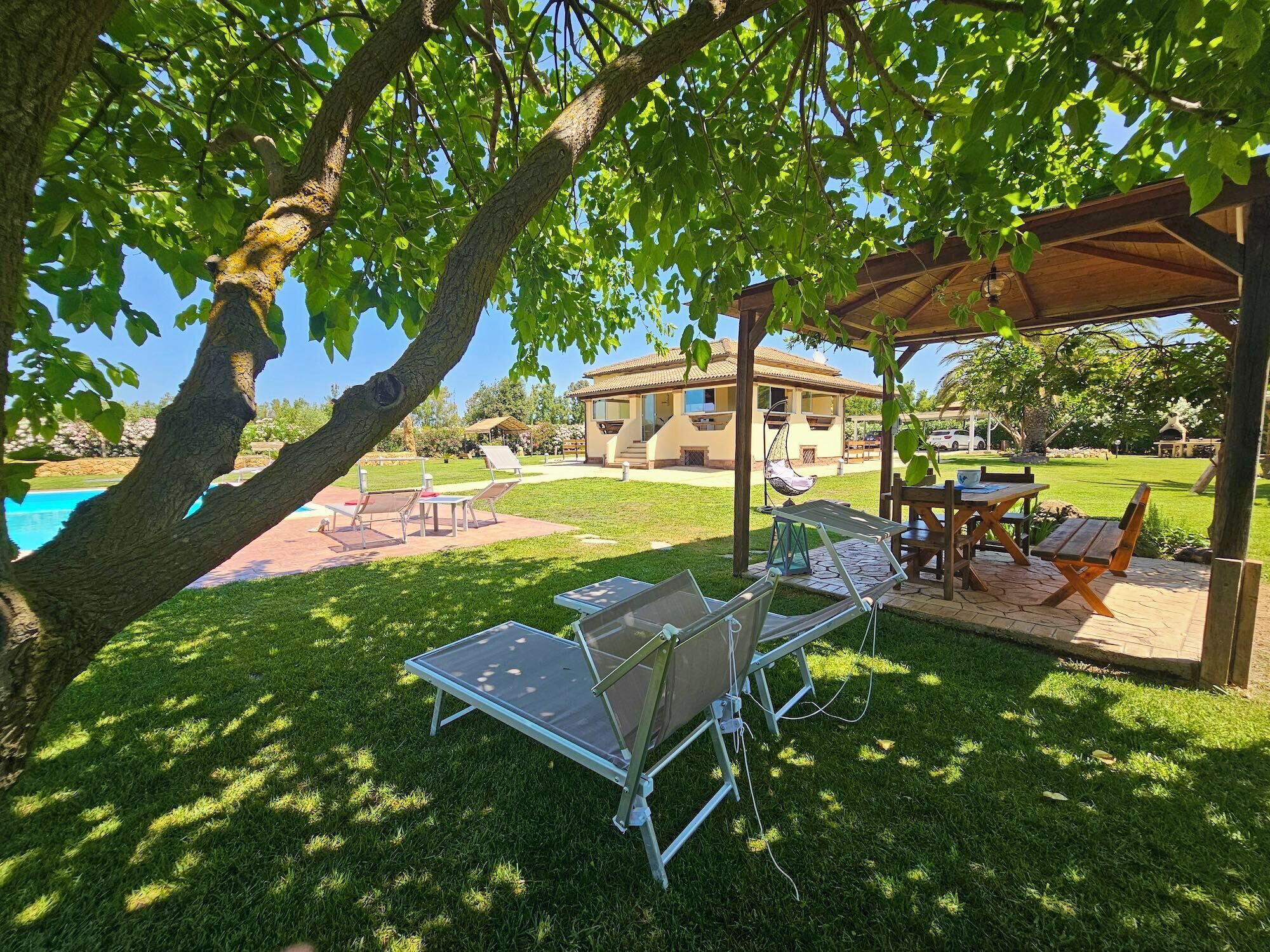 Un espace extérieur aménagé avec une piscine, du mobilier de jardin et une pergola.