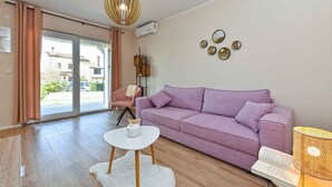 Un salon moderne avec un canapé violet, une table basse blanche et un luminaire suspendu original.