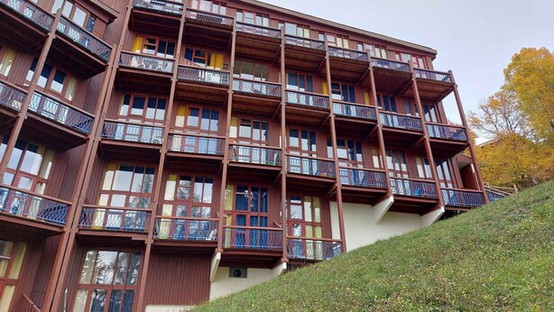 Un hotel de varios pisos con balcones en cada planta, situado en una ladera.