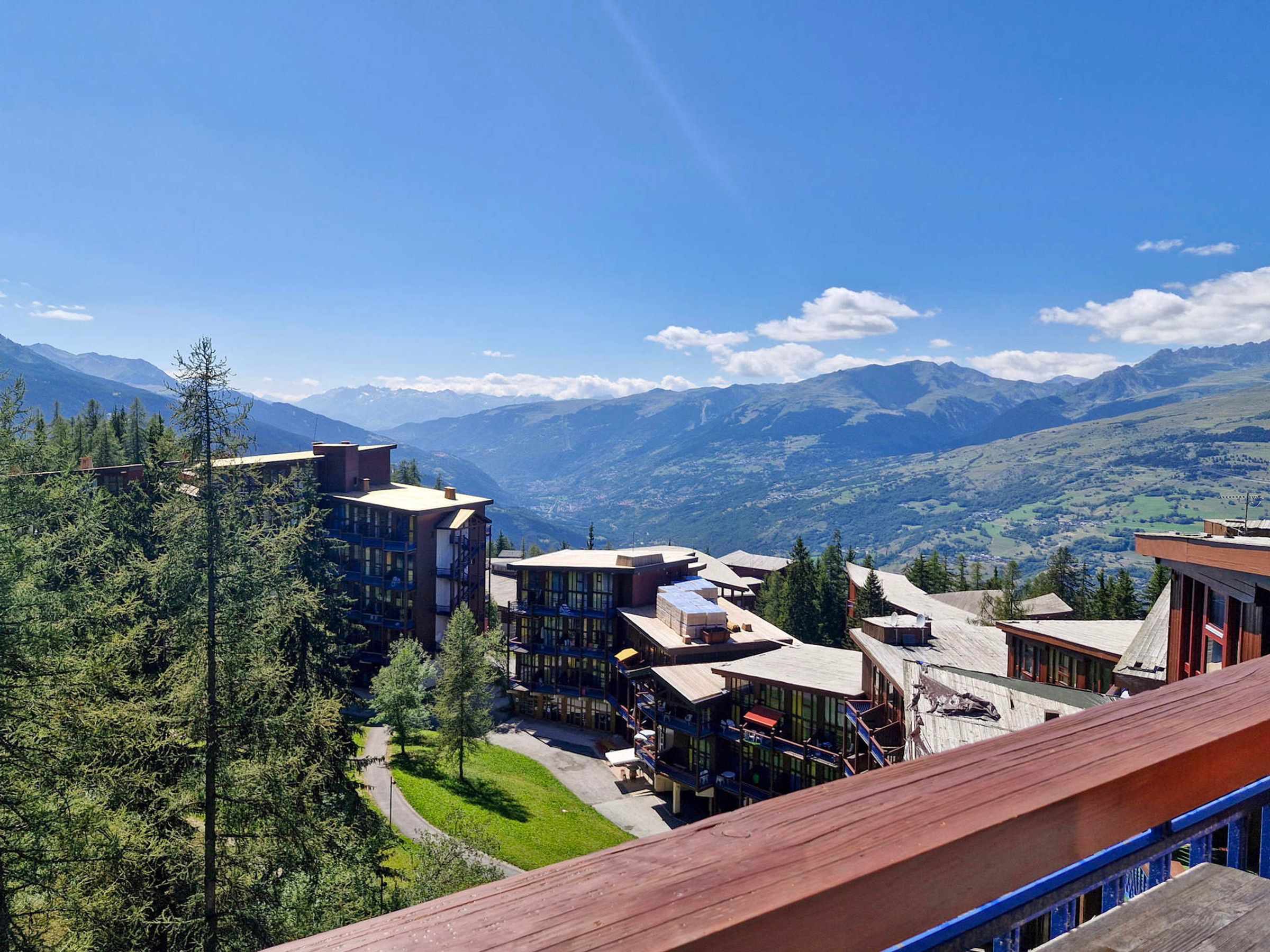 A mountain resort with modern buildings, a clear sky, and a view of the surrounding mountains.