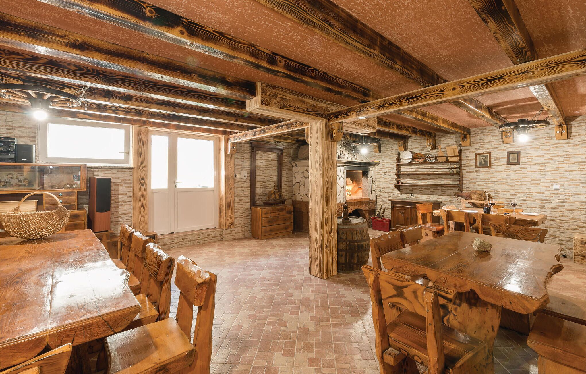 Un intérieur rustique avec des poutres apparentes, une cheminée en briques et un coin repas agrémenté de meubles en bois.